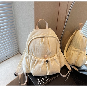 Detail view showing drawstring front pocket and smooth nylon texture of the cream backpack