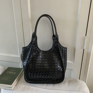 Close-up of black woven leather bucket bag with intricate Intrecciato texture