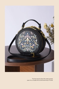 Detailed close-up of intricate floral embroidery on a vintage style black round handbag