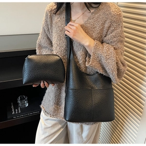 Detail of black lychee grain leather hobo bag and matching pouch on a model's arm