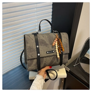Détail du sac à dos gris texture vintage avec sangles noires et breloque décorative