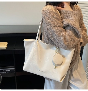 Detail of a large beige textured tote bag with a small round pouch for daily commuting