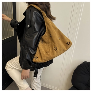 Détail du sac à bandoulière en daim marron avec découpes laser fleurs et style hobo