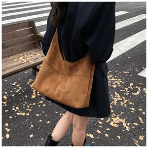Dettaglio di una grande borsa hobo in pelle scamosciata marrone portata a spalla all'aperto