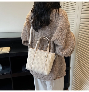 Detail of off-white woven bucket bag texture with top handle and crossbody strap