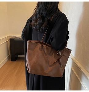 Close-up of large brown faux leather tote bag with round coin purse and gold logo