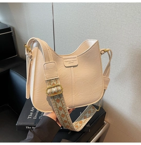 Detail of cream crossbody bucket bag with textured leather and patterned strap