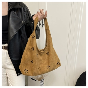 Détail d'un sac hobo en daim marron avec motifs floraux découpés au laser et grand format