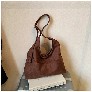 Dettaglio di una borsa hobo in camoscio marrone con tasca su valigia argentata