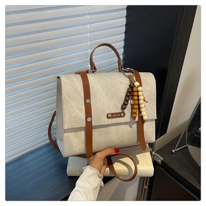 Détail du sac fourre-tout en toile avec lanières marron et breloque en perles sur stores