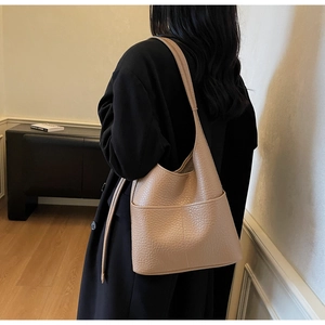 Detail view of large apricot hobo bag featuring litchi grain texture and side pocket