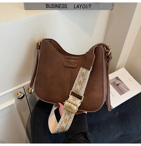 Gros plan du sac demi-lune marron vintage avec bandoulière tissée et détails en cuir mat
