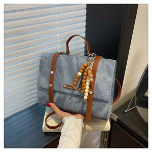 Détail du tissu en denim bleu avec poignées en cuir marron et breloque en perles de bois