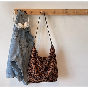 Close-up of leopard print bucket bag with leather strap hanging on a wooden hook