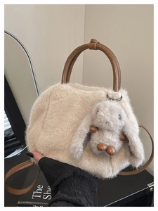 Detail der flauschigen Kunstpelz-Handtasche mit Ledergriffen und niedlichem Hasen-Anhänger