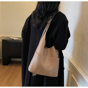 Detail of light khaki textured leather shoulder bag featuring symmetrical front pockets