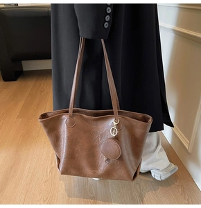 Close-up of brown faux leather tote bag with MINIMALIST & CO text and small round coin purse