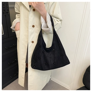 Détails de motifs floraux ajourés sur un sac cabas noir en cuir givré pour femme