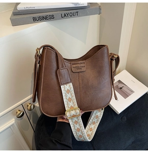 Detail of a brown leather hobo bag with a stylish patterned wide jacquard shoulder strap