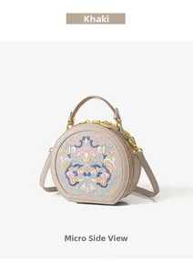 Close-up of khaki round bag featuring detailed floral embroidery and gold zippers