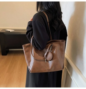 Close-up of brown leather tote bag showing large capacity and vintage texture on model