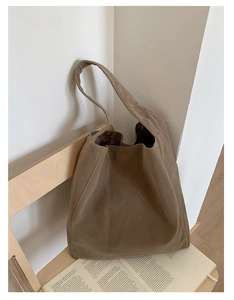 Close-up of khaki suede hobo tote bag texture on a minimalist wooden chair