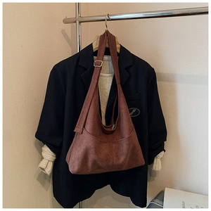 Dettaglio della borsa tote in pelle scamosciata marrone con cuciture a V e tracolla