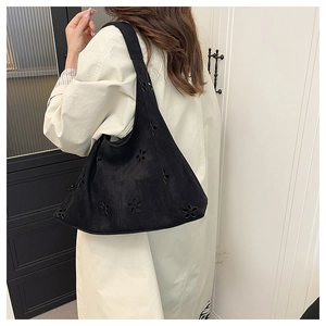 Détails des motifs floraux découpés au laser sur le sac bandoulière en daim noir mat