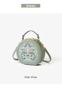 Close-up of floral embroidery on a green round crossbody bag with golden zippers