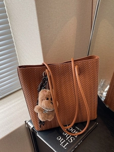 Vintage brown woven tote bag with classic herringbone pattern and plush dog charm
