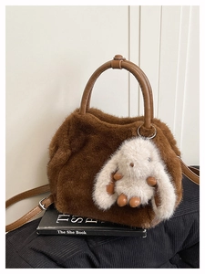 Detail einer braunen Plüschtasche mit weißem Hasenanhänger und verstellbarem Riemen