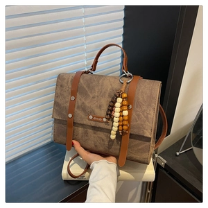 Détail du sac en cuir mat marron texturé avec une breloque en perles de bois colorées