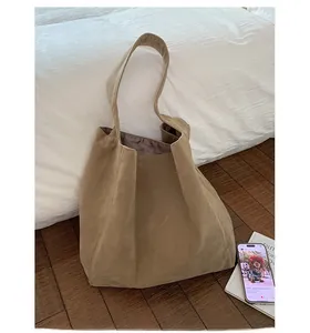 Close-up of a large khaki suede tote bag in a minimalist retro style on a wooden floor