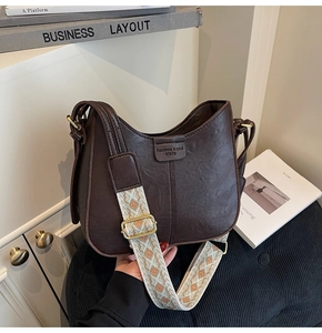 Détail d'un sac demi-lune marron rétro avec sangle jacquard aux motifs géométriques