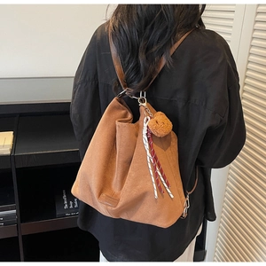 Detailansicht einer braunen Wildleder-Hobo-Tasche mit Bärenanhänger an der Schulter