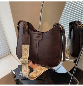 Détail du sac hobo marron foncé avec finition vintage et bandoulière tissée colorée