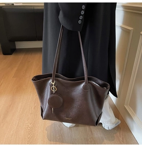 Detail of dark brown leather tote bag with a small coin purse and gold embossed text