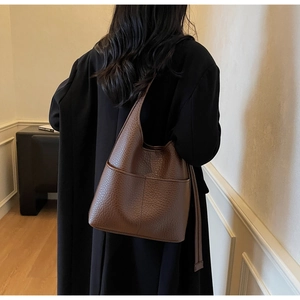 Macro detail of brown lychee grain leather hobo bag with front pockets on model