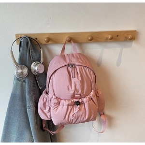 Close-up of pink lightweight nylon backpack with drawstring front pocket and mesh side bag