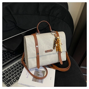 Vue détaillée d'un sac messager beige vintage avec perles en bois sur un fauteuil