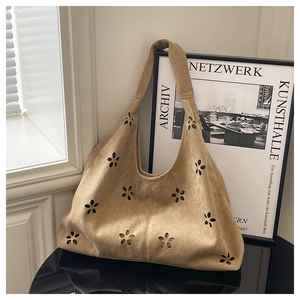 Détail du sac hobo en daim camel avec motifs floraux découpés au laser et texture riche