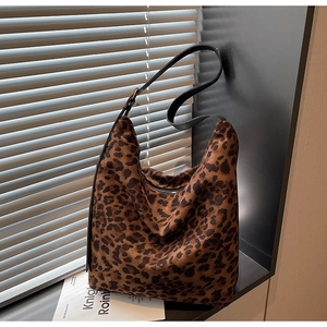 Detail view of leopard print hobo bucket bag with black leather strap and metal zipper