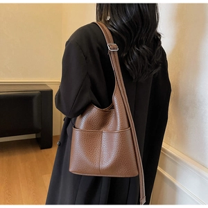 Detail view of brown crocodile texture shoulder bag with adjustable metal strap buckle