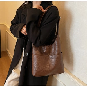 Close-up of dark brown lychee grain leather shoulder bag with wide strap and front pocket
