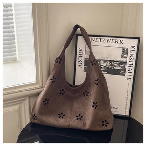 Détails des motifs floraux découpés au laser sur le sac fourre-tout marron en daim