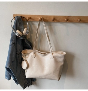 Detail of off-white tote bag with textured leather, mini pouch and gold hardware hook
