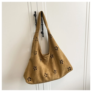 Détail de motifs floraux découpés au laser sur le grand sac cabas hobo en daim marron