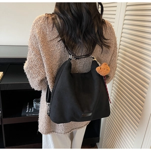Detail der schwarzen Wildleder Hobo Tasche mit süßem Plüschbären und Karo-Schleife