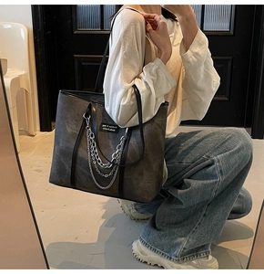 Détail d'un sac cabas gris foncé avec triples chaînes métalliques et texture mate vintage