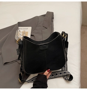 Détail du sac hobo noir avec une large bandoulière tissée aux motifs ethniques